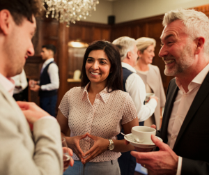 Diverse professionals networking and smiling happily at a formal corporate event, discussing business and building connections in an elegant venue.